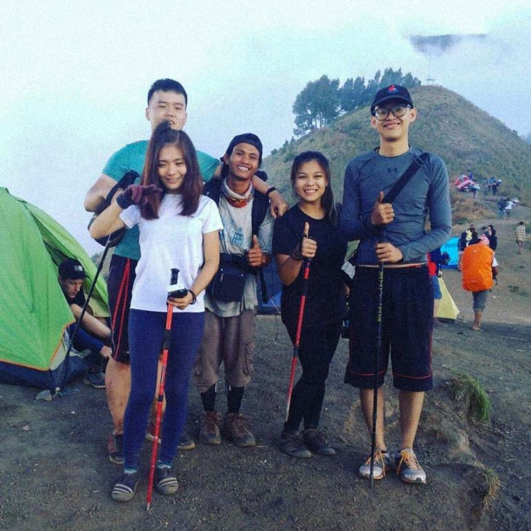 A hiking family and their guide pose at their camp on the way up to Mt. Rinjani.