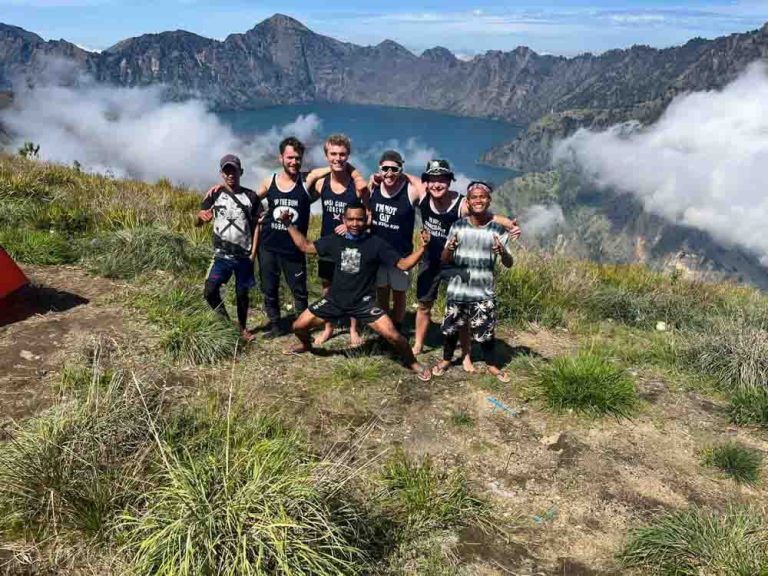 Four friends pause with three guides at their campsite overlooking Mt. Rinjani's crater lake.