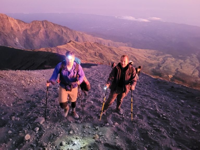 Trekkers reaching the Mt. Rinjani summit at the crack of dawn, with headlamps still lighting the way.