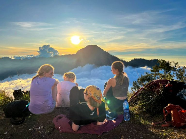 Friends soak in the morning sun as they relax after trekking to the summit of Mt. Rinjani.
